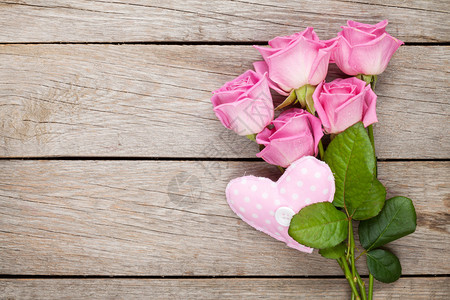 粉红玫瑰花束和手工制作的心脏玩具在图片