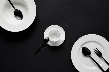 黑桌上各种板杯黑勺子和叉图片