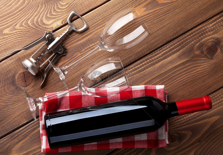 木桌背景上的红酒瓶眼镜和开瓶器顶视图图片