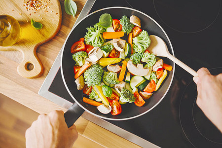 将新鲜健康蔬菜煎成炉灶上用锅子煎的图片