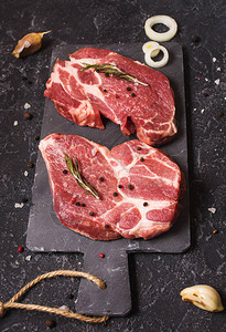 生肉牛排配黑色石头背景上的调味料牛排准备好烹饪烧烤概念图片