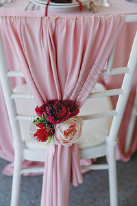 粉红色酒红色和白色调的遮阳篷下的婚礼宴会的美丽装饰餐桌旁饰有薄布和胸花图片
