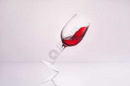 近距离拍摄倾斜葡萄酒杯在反射表面和背景图片
