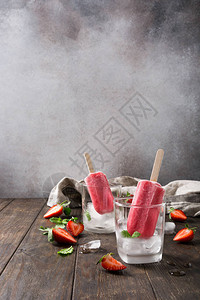 自制草莓冰棒在玻璃杯中加冰草莓和薄荷在旧木背景上具有复制空间的健康图片