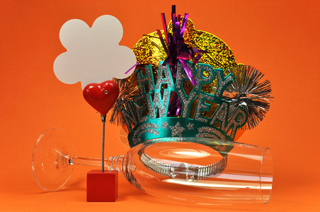 新年快乐派对的装饰品包括香槟杯和帽子桌位持有者以及空白卡背景图片