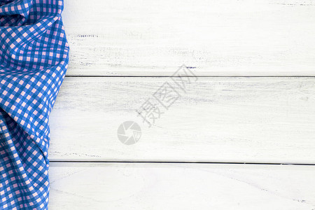 空白木桌上的皱褶蓝色方格桌布或餐巾纸图片