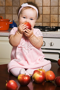 可爱的小女孩在厨房吃苹果图片