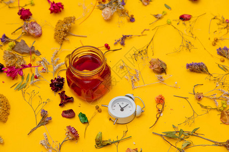 黄色背景中带小闹钟和香草的红茶杯图片