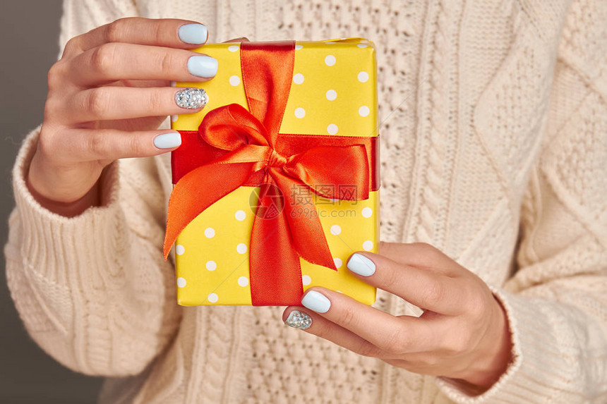 白色圆点图案在黄纸和红弓上赠送礼物和展示爱意时装冬季美甲图片
