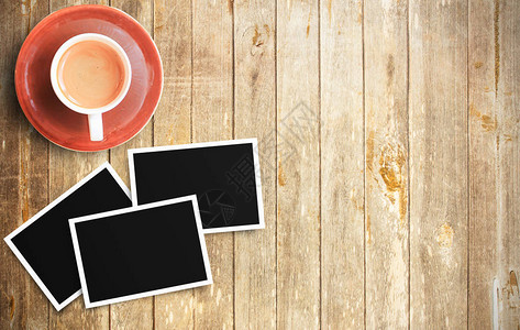 木制桌上的两块咖啡杯和两张空白照片框背景图片