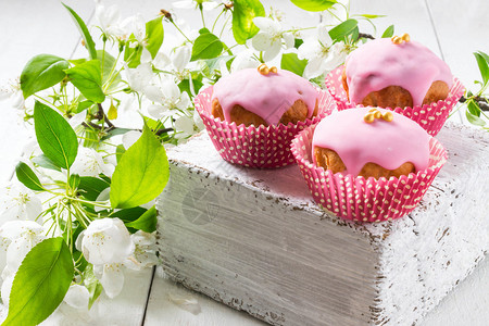 厚的白木板上有粉红玻璃和糖珠的新鲜自制纸杯蛋糕图片