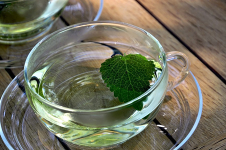 玻璃杯装柠檬香脂茶和一片叶子图片