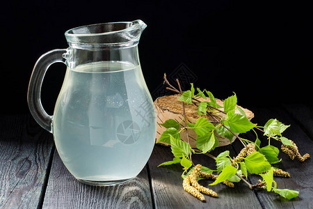 春季有用的维生素饮料水罐中新鲜的冷桦汁和深色背景中的桦树枝健康和维生图片