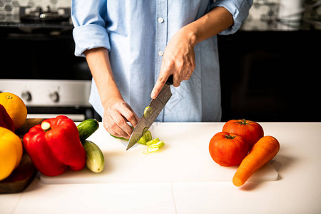 女人在厨房里切黄瓜年轻女子用大刀在塑料板上切黄瓜图片