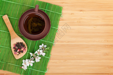 一壶茶与樱花枝在绿竹帘上背景图片