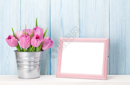 粉红新郁金香花束和空白照片框在木墙前架图片