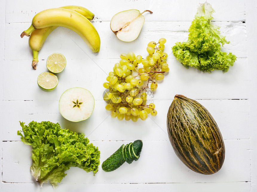 白色木制背景的绿色蔬菜和水果收图片