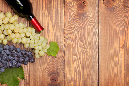 红酒瓶子和木桌背景的葡萄图片