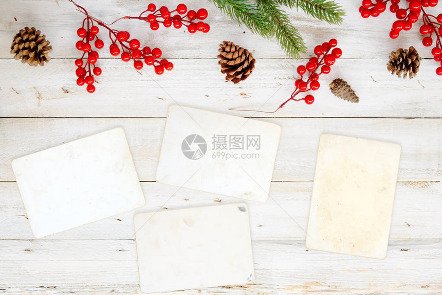 圣诞主题背景与空白相纸和白色木桌上的装饰元素具有边框和复制空间设计的创意平面布局图片