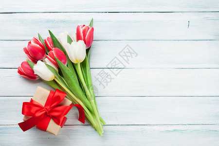 木制背景上的红色和白色郁金香花束和礼品盒图片