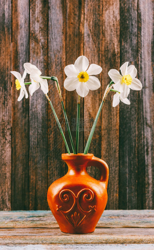 一束花朵的鲜花留在一个老陶瓷炉子里在木制古老的石图片