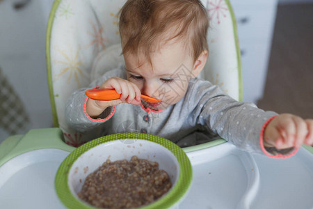 坐在家里的婴儿桌边吃粥的可图片