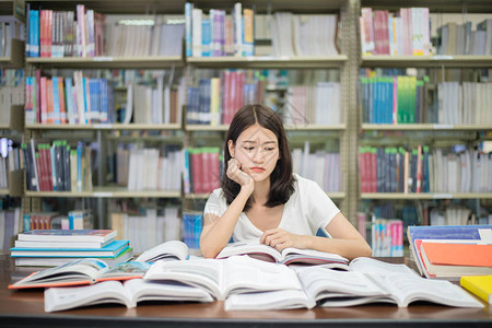 心灰意冷亚洲女学生在图书馆看书很无聊背景