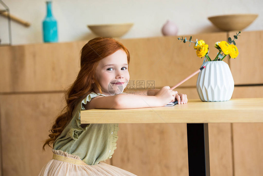 可爱的红发美女在咖啡厅坐在桌边用铅笔画图片