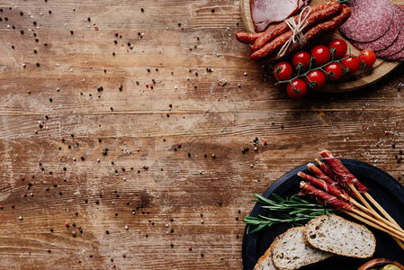 木桌上放着橄榄的切菜板美味的熏香肠意大利腊肠面包西红柿和香草图片
