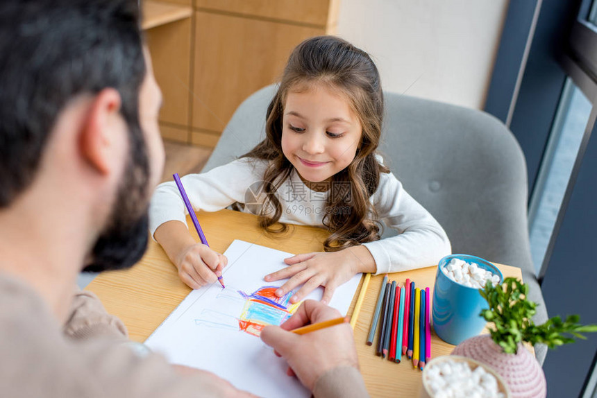 父亲和女儿与彩色铅笔一起绘图片