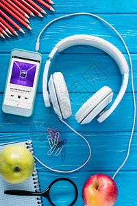 屏幕耳机苹果和蓝木背景文具上的苹果音乐应用软件的智能图片