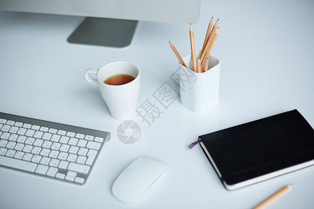 茶杯键盘玻璃铅笔记本和桌上图片