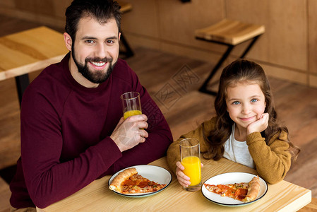 快乐的父亲和女儿在咖啡馆喝橙图片