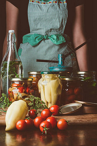 妇女在厨房玻璃罐中站在保留蔬菜附近的妇女形图片