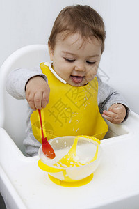 一个小孩坐在桌子旁用勺子吃饭一个快乐的孩子学会吃图片
