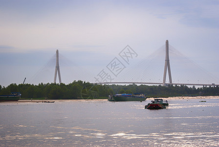 芹苴吊桥是东南亚主跨最长的桥梁由日本人建造从芹苴市看一艘大型驳船搁浅在沙洲上背景图片