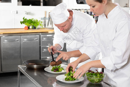 两位顶尖厨师在美食餐厅或酒店的专业厨房里准备牛肉菜图片