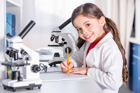 小女孩在化学实验室做笔记和笑着图片