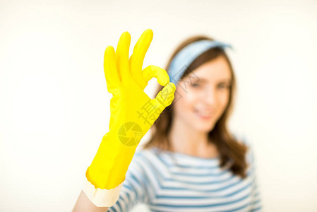 穿着黄色橡皮手套的年轻笑着女人表现出与白图片