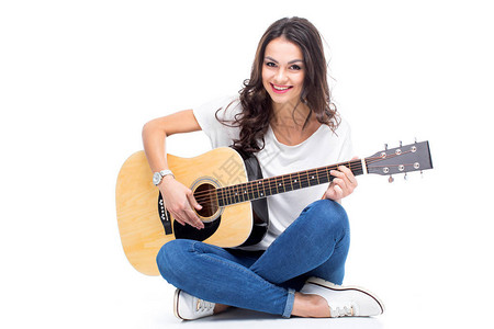 微笑的年轻女人坐着弹吉他在图片