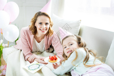 快乐的母亲和女儿拿着美味的草莓蛋糕图片