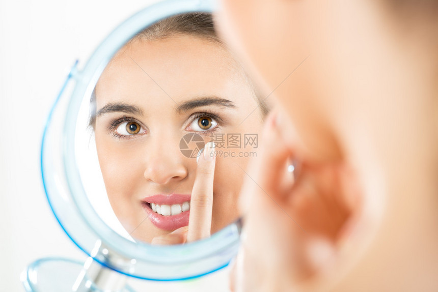 镜子里反射的摄影美丽的女孩用奶油涂在她图片