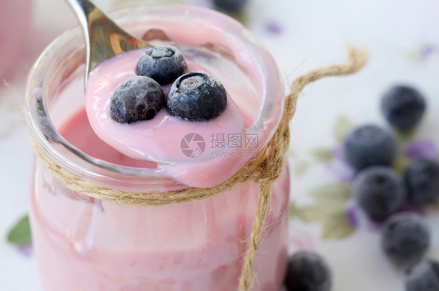 在桌布上玻璃杯中自制的蓝莓酸奶图片