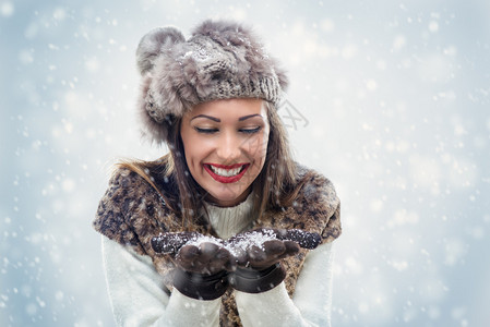 穿冬衣吹雪花的年轻美女手握着雪花她图片