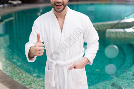 在浴袍中微笑的年轻男子在温泉图片