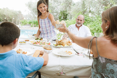 快乐的家庭坐在户外的餐桌旁一起吃饭图片