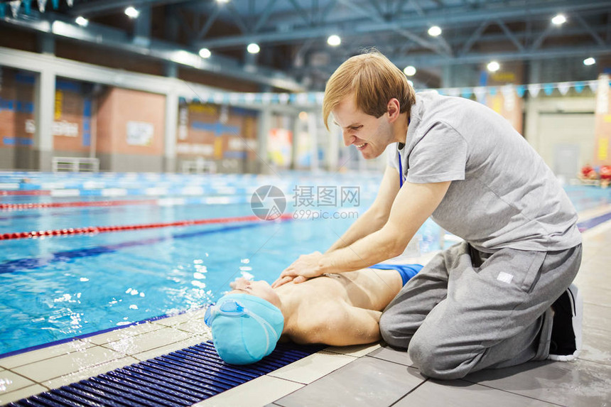 年轻男子或游泳教练在事故发生后为一名学员提供急救的青少图片
