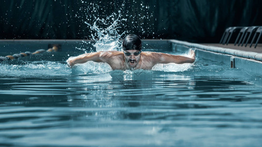 充满活力和健康的游泳者戴着帽呼吸在游泳池进行蝶泳年轻人Fitsport背景图片