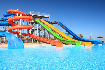 五颜六色的水上乐园管和热带水上乐园的游泳池图片