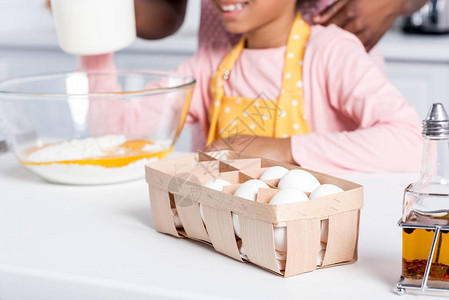 在厨房做围裙烹饪时看到非裔美国人儿童在厨房鸡蛋和油料上露图片
